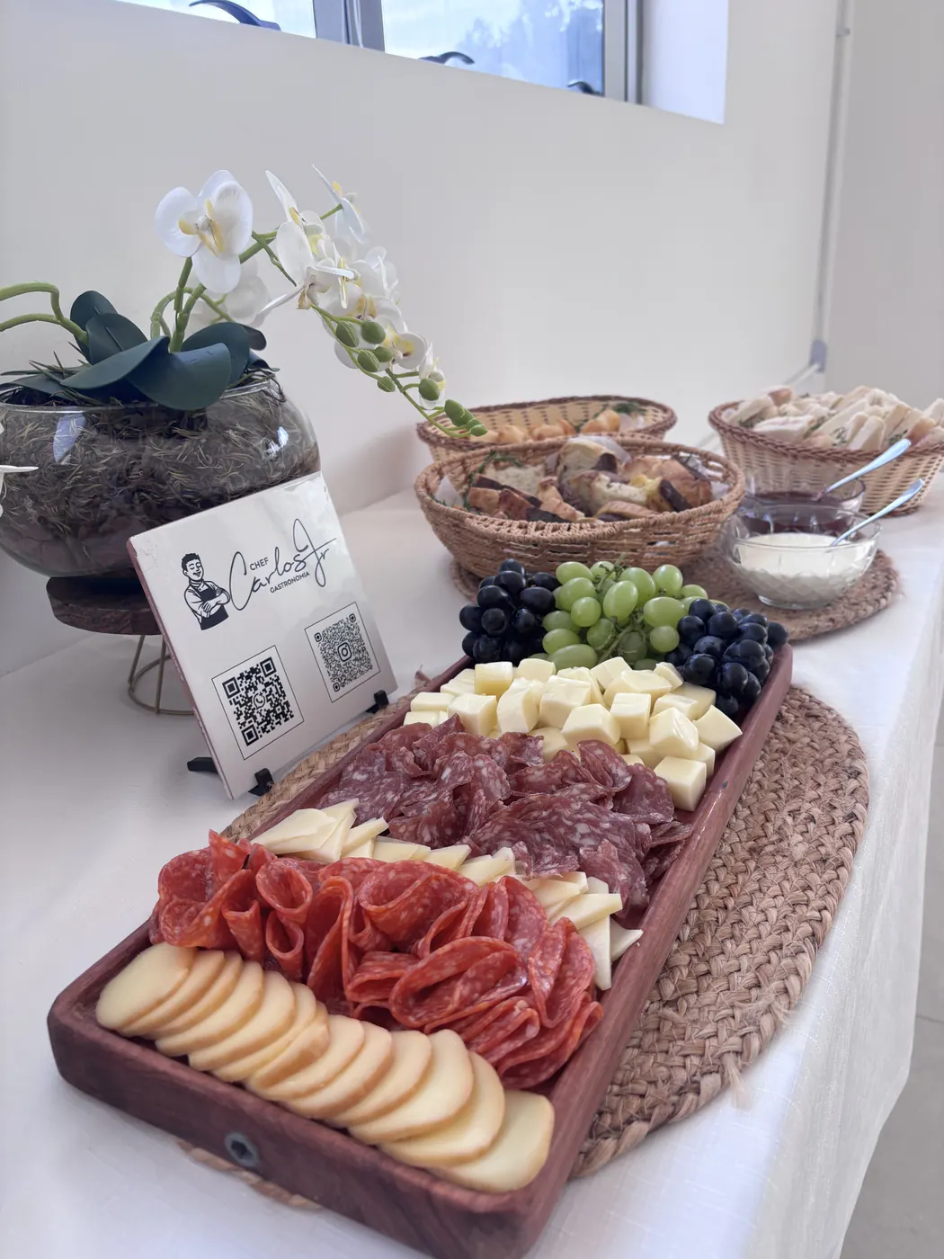 Tábua de embutidos, queijos e uvas ao lado do cartão do Chef