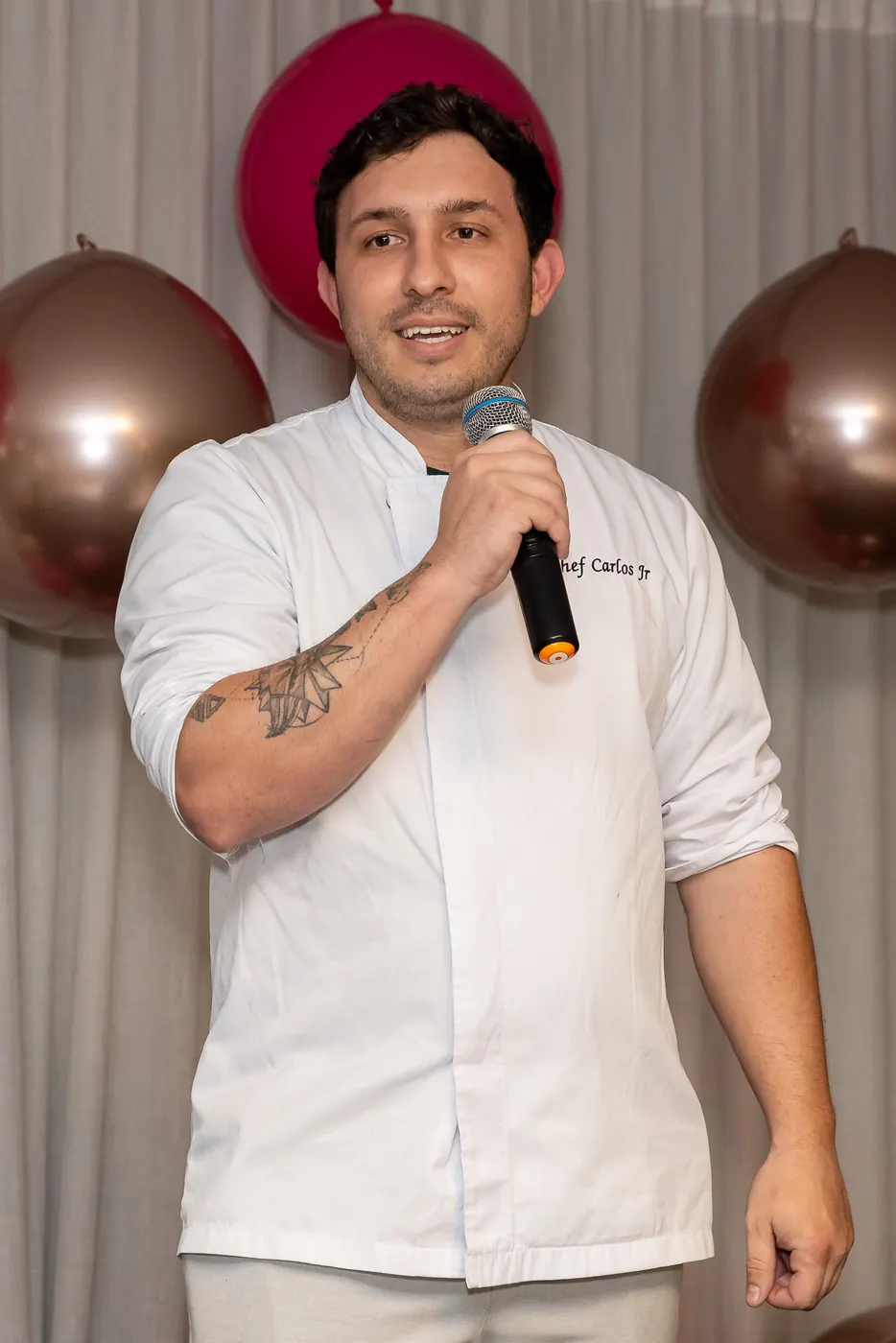 Chef Carlos Junior falando ao microfone durante um evento